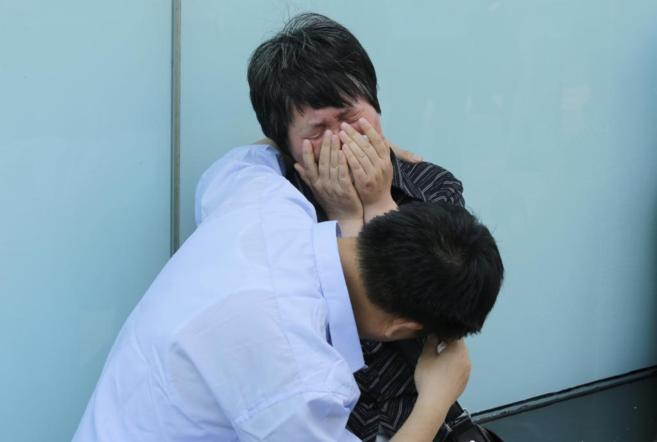 Una mujer, cuyo hijo estaba a bordo del vuelo MH370, llora junto a su...