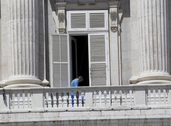 Dos trabajadores trabajan en el balcn del Palacio Real donde...