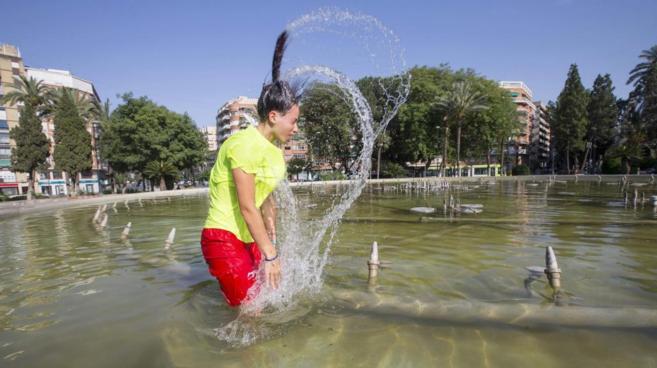 Una joven se da un baño en una fuente el 14 de junio en Murcia, donde...