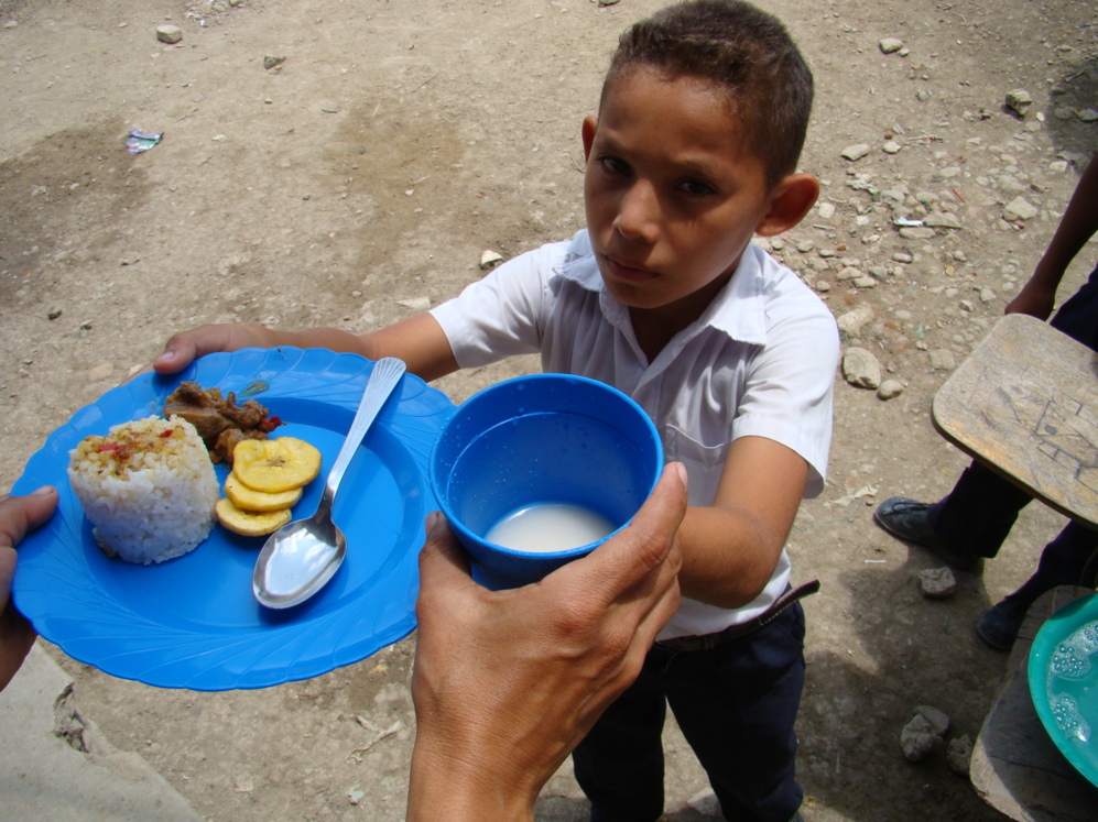Un nio recoge su plato de comida en el colegio en El Hobo.