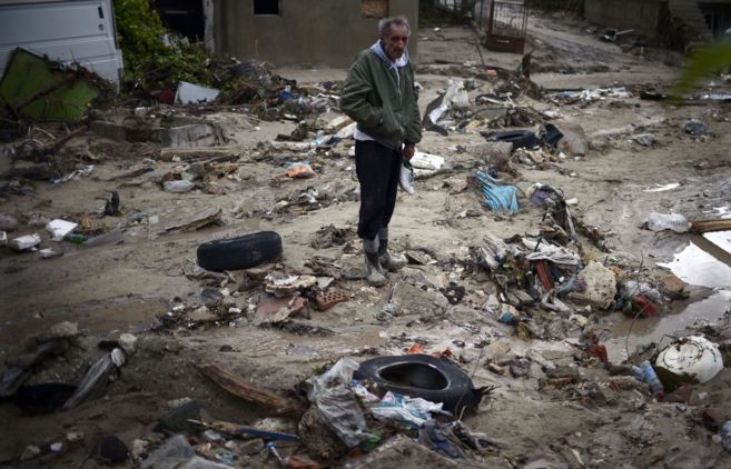 Un hombre, entre los escombros de casas destruidas por las lluvias...