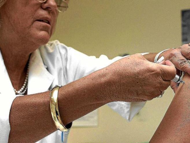 Una enfermera administra una vacuna a una paciente.