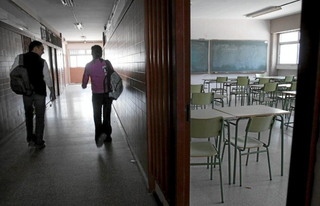 Dos alumnos pasan junto a un aula vacía en un instituto sevillano.