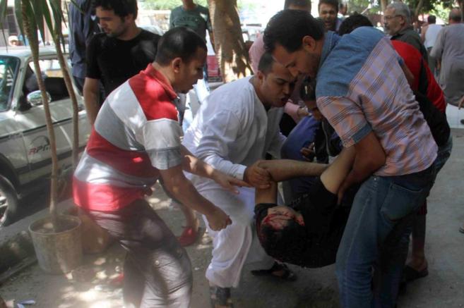 Ciudadanos de El Cairo ayudan a un hombre herido en los choques en las...