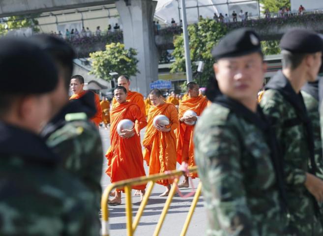 Monjes budistas desfilan tras una fila de soldados tailandeses.