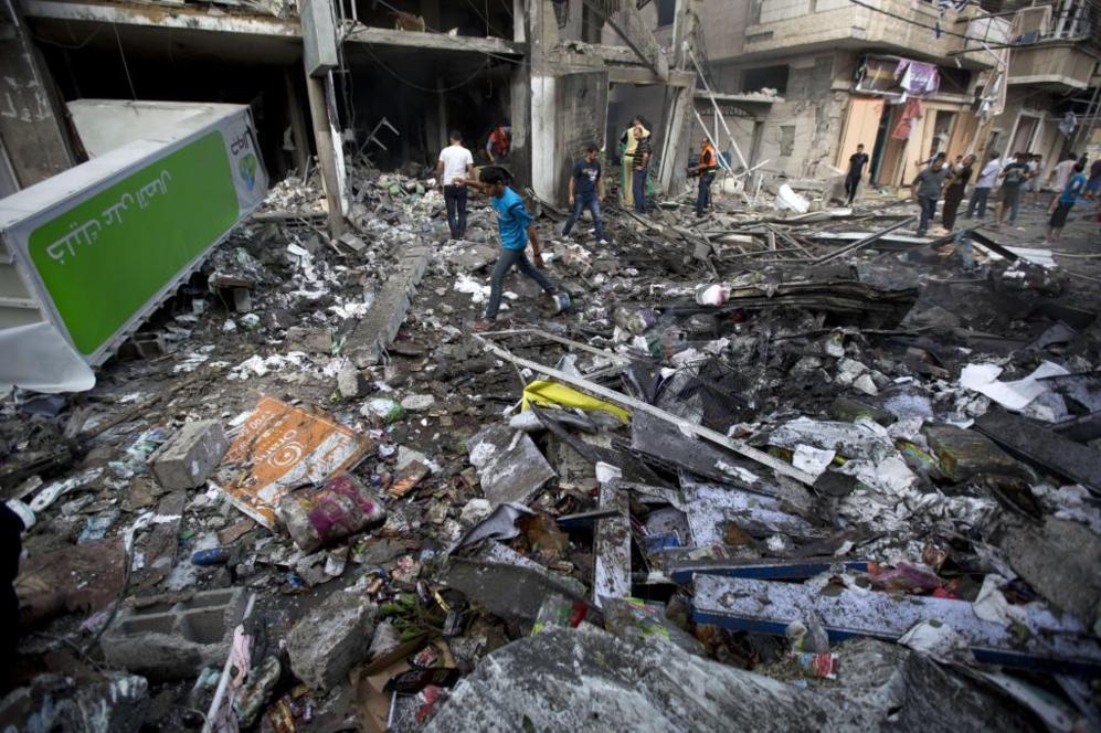 Palestinos caminan sobre sus hogares destrozados tras un ataque areo...
