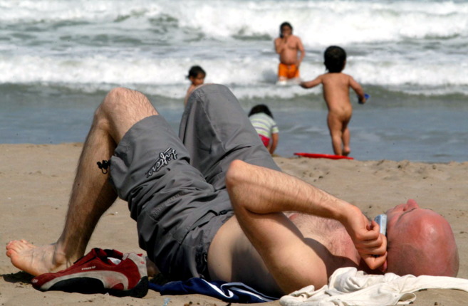 Un hombre usa el telfono mvil mientras toma el sol.
