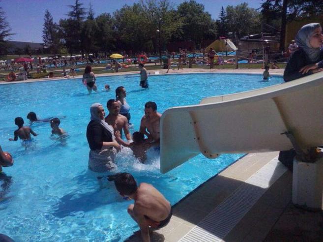 Una piscina municipal con nios y mayores.
