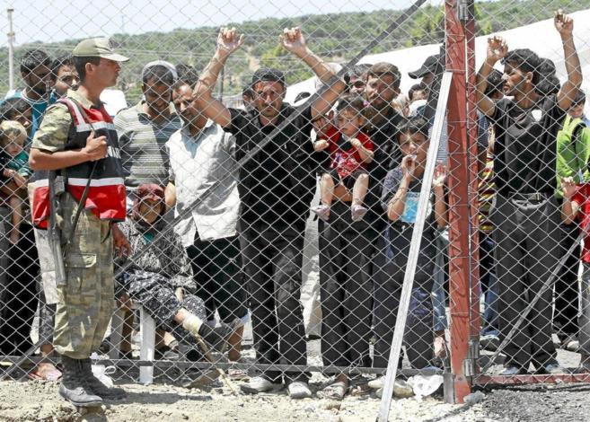 Refugiados sirios tras la valla del campo de refugiados de Boynuegin,...