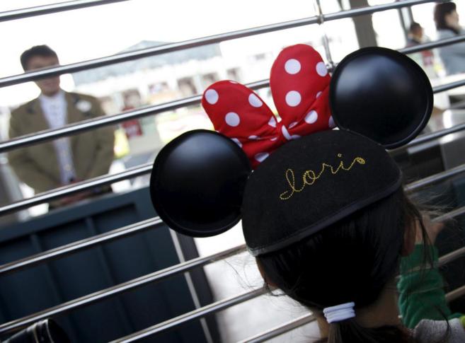 Una niña de cinco años, con un gorro de Minnie Mouse, espera para...