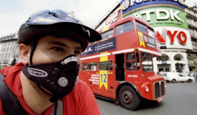 Un ciclista cruza Piccadilly Circus con una máscara protectora en la...