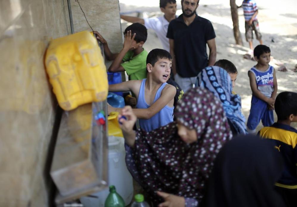 Nios rellenan botellas de agua en la fuente pblica de Rafah.