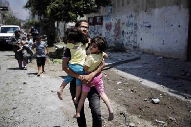 Un padre palestino saca a sus hijas del barrio de Shejaia, atacado por...