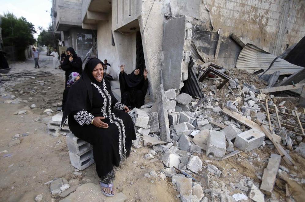 Varias mujeres palestinas reaccionan al ver sus casas destruidas por...
