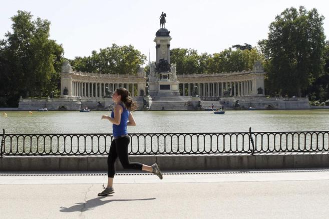 Una mujer corre frente al lago del Parque del Retiro, en Madrid.