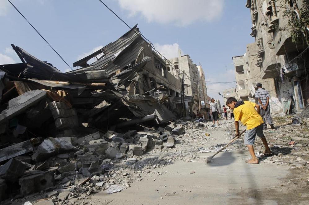Un nio palestino retira escombros del suelo a las afueras de una...