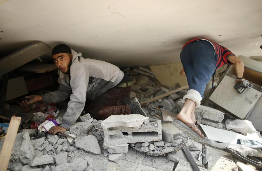 Dos palestinos buscan pertenencias entre los escombros