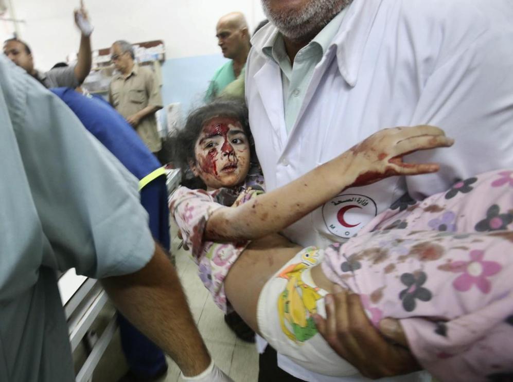 Un mdico palestino lleva en brazos a una nia herida por un ataque...