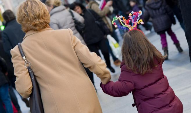 Una abuela y su nieta pasean por una cntrica calle de Madrid.