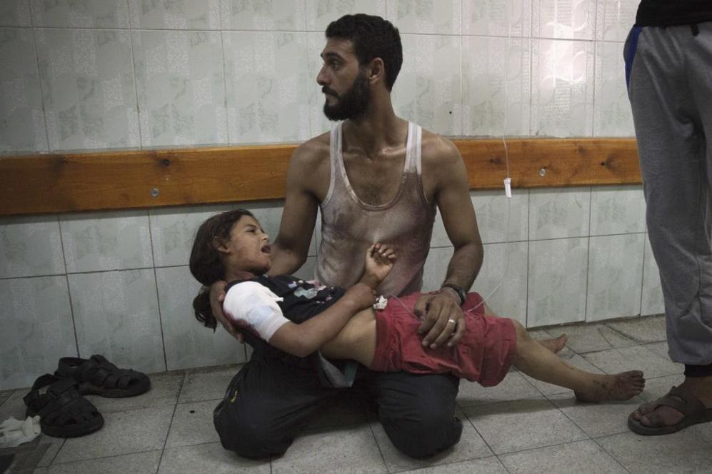 Un hombre palestino sostiene a una nia tras el ataque de un obs a...
