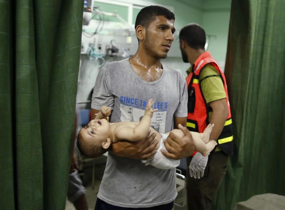 Un hombre palestino carga con un beb tras el ataque de un obs a...