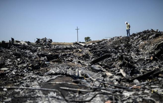 Un hombre mira los restos del vuelo MH17 esparcidos y quemados en el...