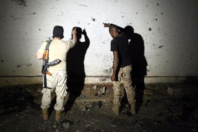 Dos soldados libios examinan un muro lleno de agujeros de bala en el...