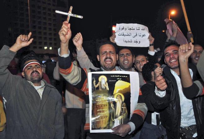 Revueltas en Egipto. Un grupo de cristianos coptos muestra una cruz...