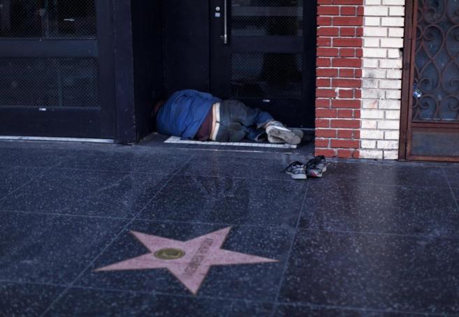 Un hombre sin hogar duerme a la entrada de un edificio en Hollywood.
