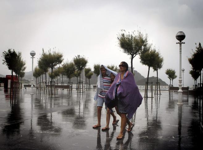 Dos turistas se protegen de una tormenta en San Sebastin, el pasado...