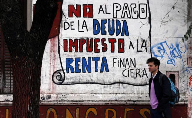 Un hombre camina frente a un mural en el centro de Buenos Aires.