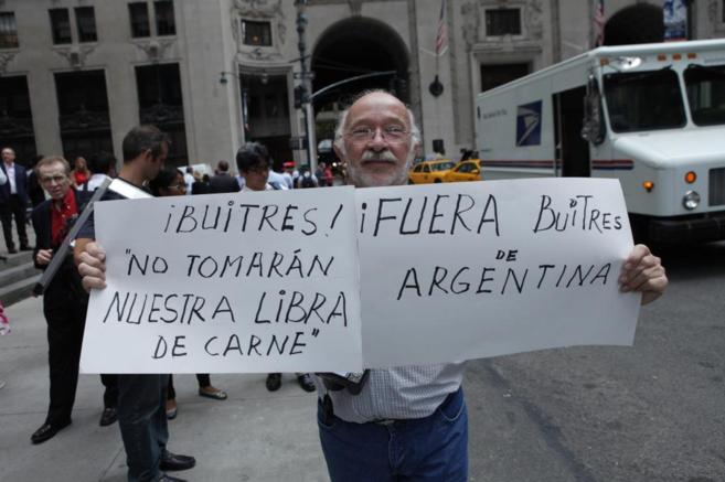 Un argentino sostiene un cartel contra el pago a los fondos...