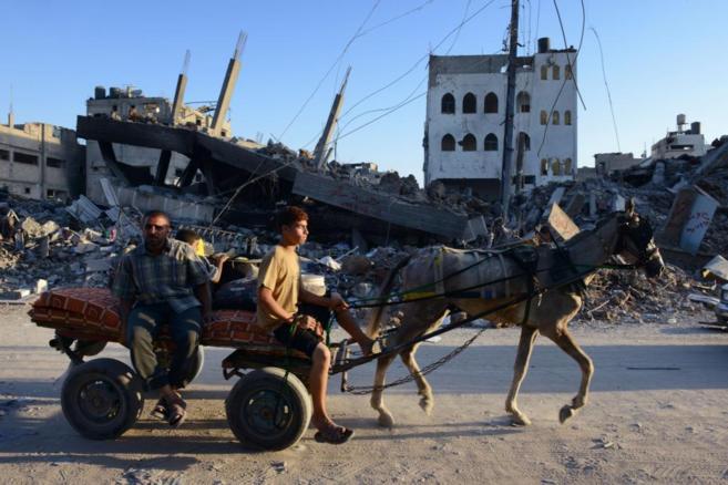 Ciudadanos de Gaza trasladan sus pertenencias por un barrio derruido...