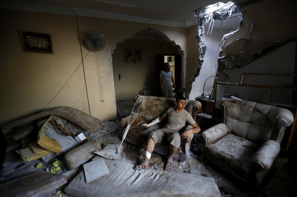 Un palestino observa cómo ha quedado sus casa tras ser alcanzada por...