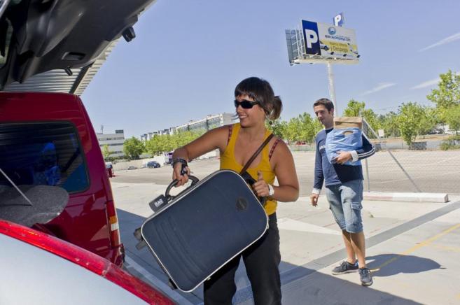 Dos jóvenes descargan sus maletas del coche, en el aeropuerto Adolfo...