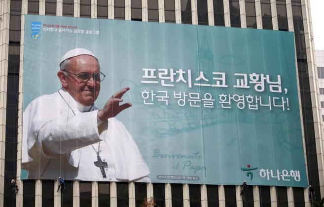 Unos trabajadores ajustan un cartel de bienvenida a Bergoglio en...