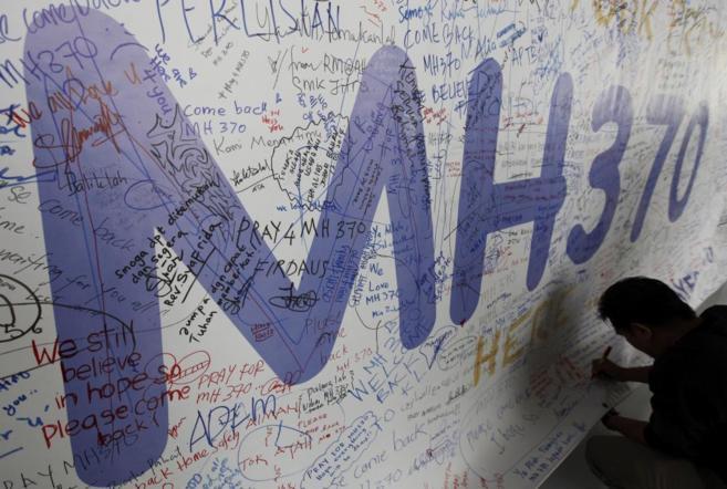 Un joven escribe mensajes de apoyo a los pasajeros del vuelo MH370 de...