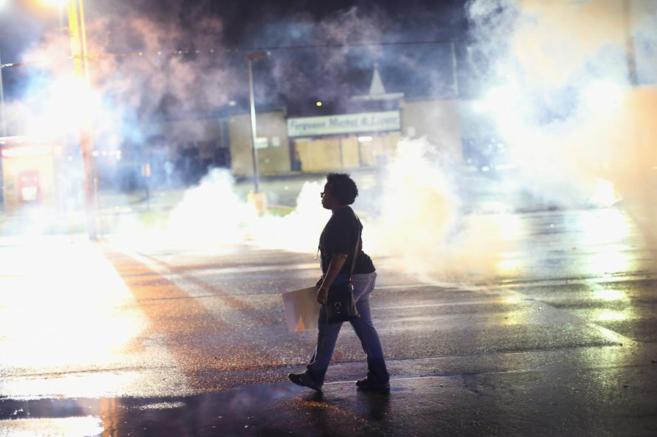 Una manifestante camina en medio de los gases lanzados por los...