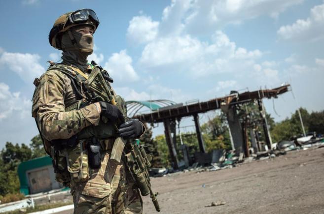 Un soldado ucraniano monta guardia cerca de una gasolinera destruida...