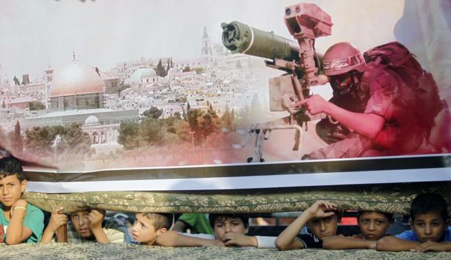Niños palestinos se asoman tras un póster gigante que muestra a un...