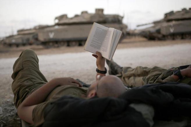 Un soldado israelí lee un libro en una zona cercana a la Franja de...