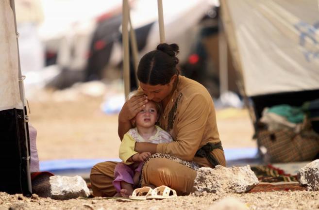 Una iraquí y su hijo se refugian en un campamento sirio tras huir de...