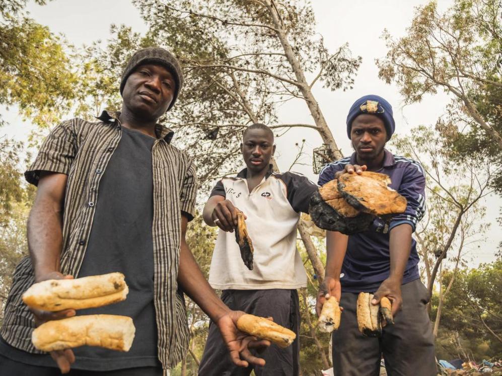 Tres subsaharianos muestran restos de pan calcinados, tras las redadas...
