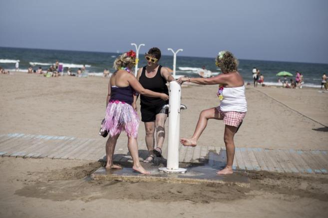 Tres turistas en la playa de la Malvarrosa (Valencia).
