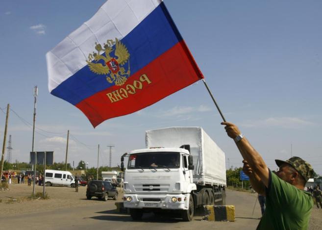 Un local agita una bandera de Rusia mientras el convoy cruza la...