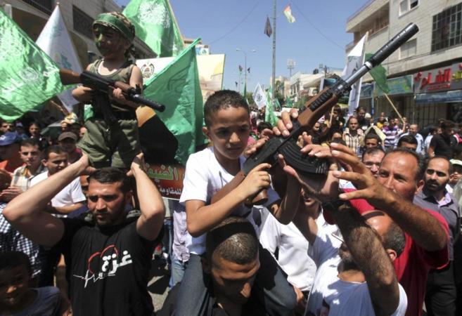 Niños palestinos armados con rifles de juguete participan en una...