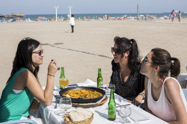 Unas turistas madrileas comen paella en la playa de la Malvarrosa.
