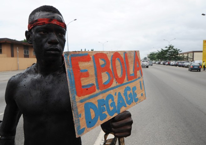 Un hombre sostiene un cartel donde se puede leer 'Ebola, vete...
