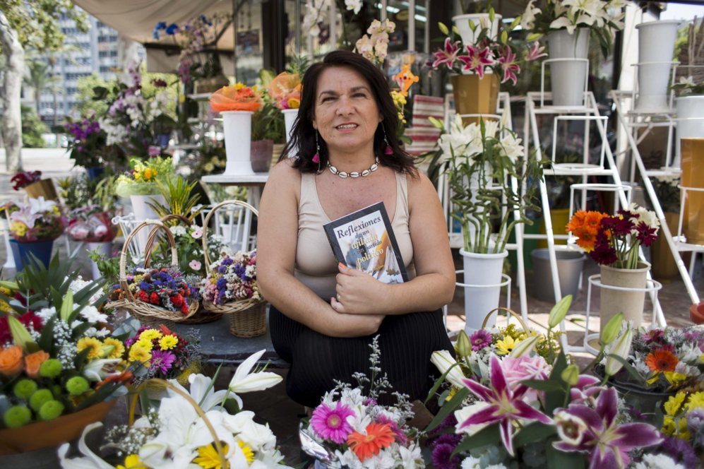 Lola Soriano posa con su libro en el puesto de flores que regenta.