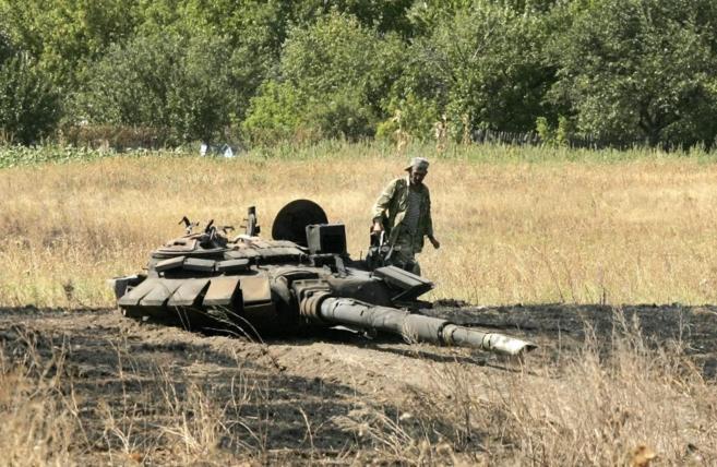Un militante prorruso observa los restos de un tanque ucraniano cerca...
